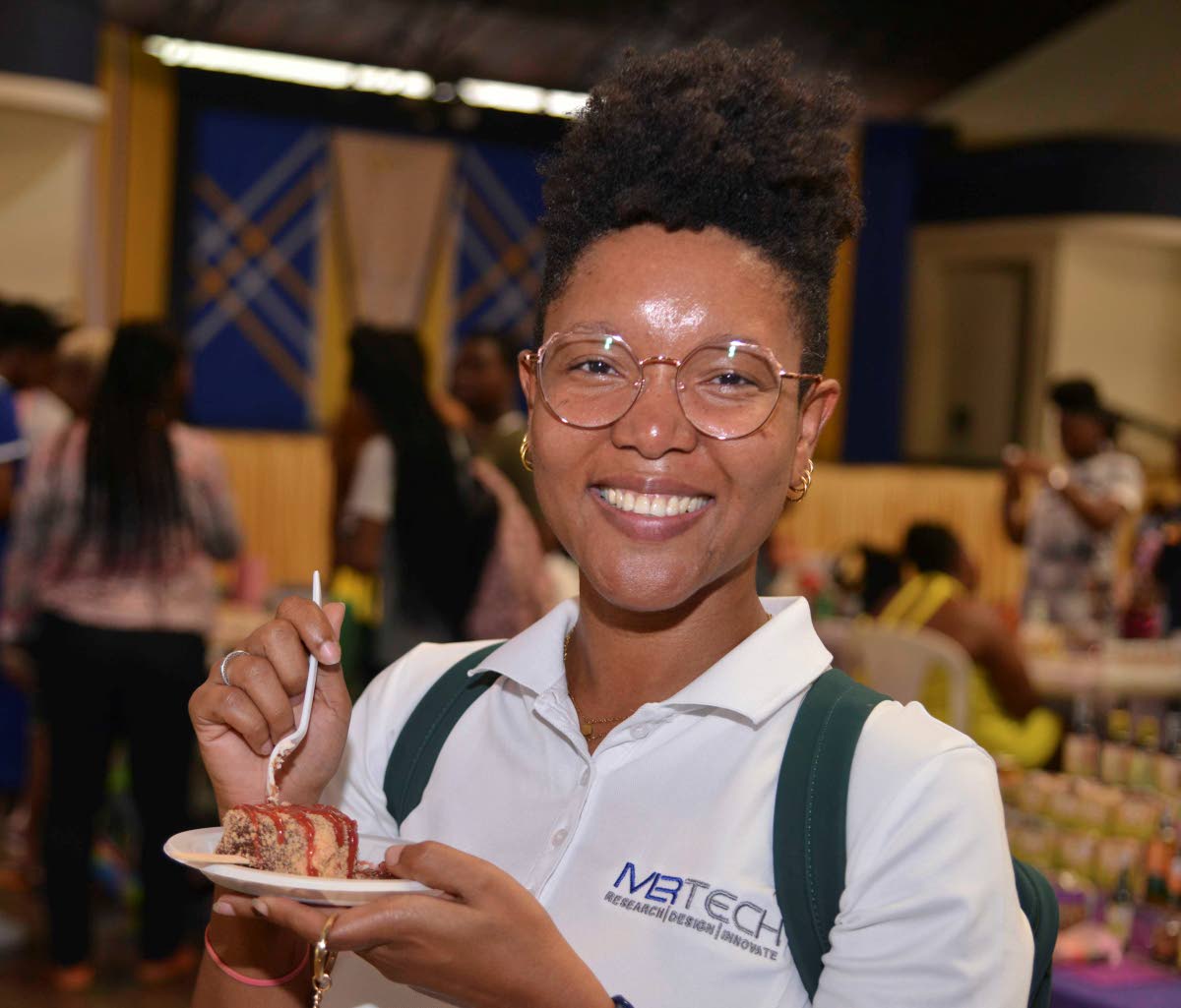 Dr Aisha Bailey of MLR Technology and Innovation enjoys a strawberry shortcake cheesecake-on-a-stick at the Drizzle Cheesecake Jamaica booth during the Health, Hair & Beauty Expo at the University of Technology on Wednesday.