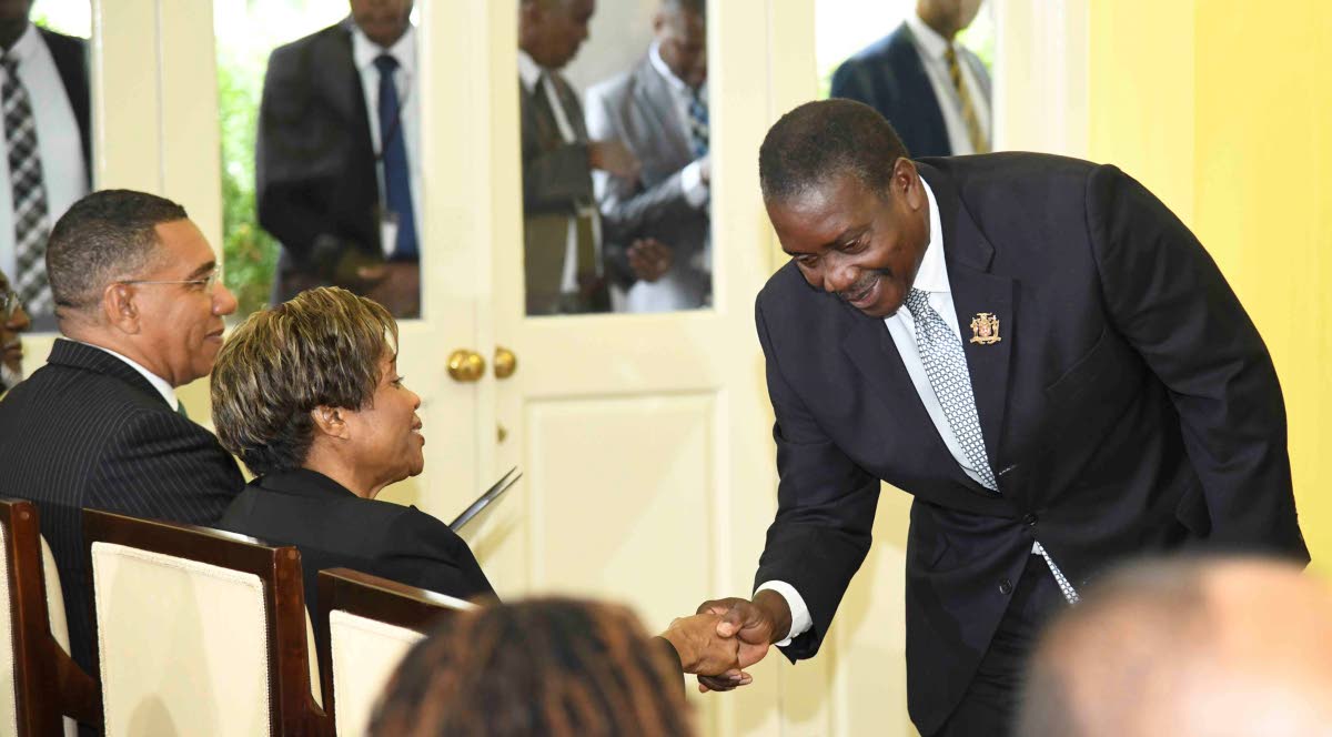 Robert Montague greets Lady Patricia Allen after being sworn in as minister without portfolio in the Ministry of Economic Growth and Infrastructure Development, with responsibility for land titling and settlements at yesterday’s swearing-in ceremony.