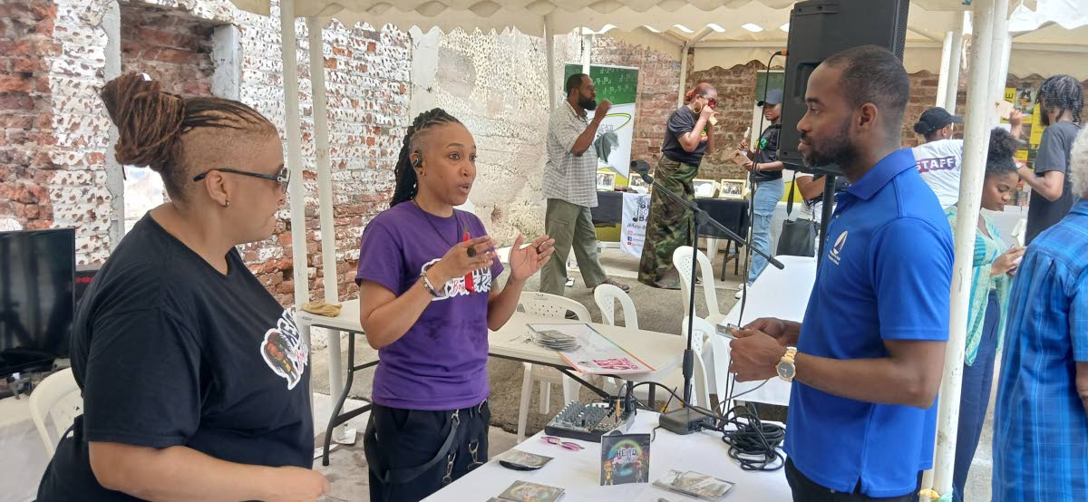 Christopher Brown (right), programme manager of the Development Bank of Jamaica Limited's BIGEE project, looks on as Tandra 'DJ Lytes' Jhagroo (left) and Lois ‘DJ Lava’ Morgan talk to him about their business, HEAD BopHERZ.
