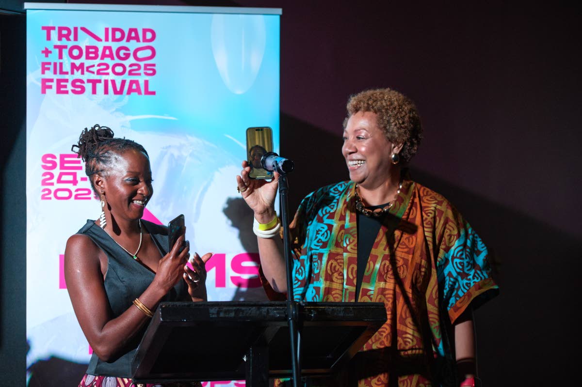 Alison Duke (right), film director, holds the phone to the microphone as Sister Nancy addresses the audience at the gala screening of the documentary on her life. Sharing in the moment is Ngardy Conteh George, producer and co-owner of OYA Media Group. 