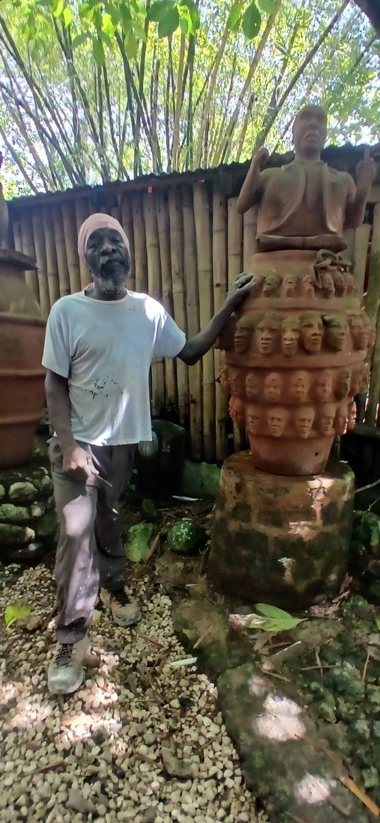 Ceramic artisan Sylvester Stephens stands beside his depiction of National Hero Marcus Garvey in ‘The Marcus Garvey Garden’ at Great Huts Eco Resort at Boston in Portland.