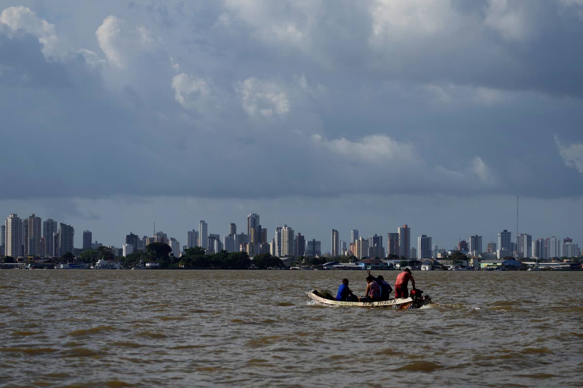 A boat sails on the bay of the Guama River with Belém, Brazil, in the background.					      