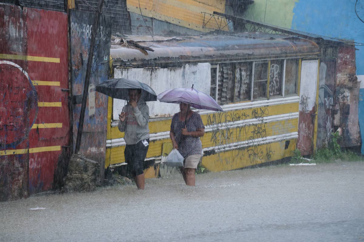 People wading through a street flooded by rains caused by Tropical Storm Melissa in Santo Domingo, Dominican Republic.