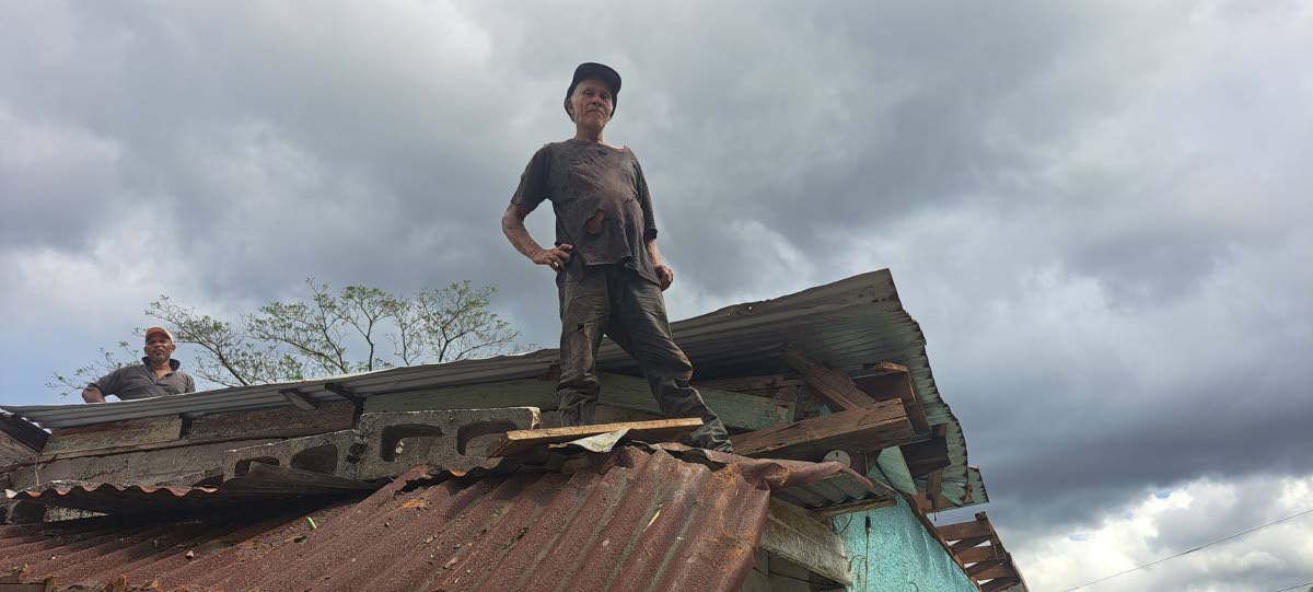 Edwin Thompson stands atop the roof of his home in Portland on Thursday, after it was damaged by Hurricane Melissa.