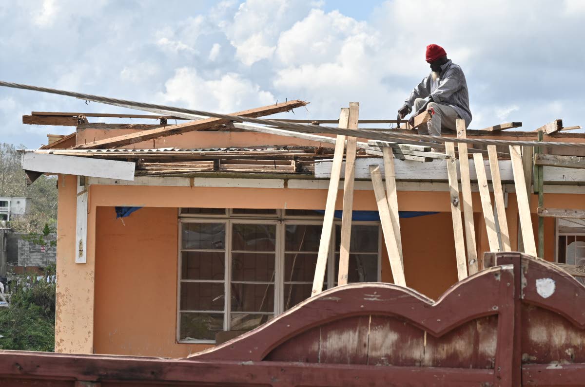 A man works at fixing his roof in Trelawny after the passage of Hurricane Melissa.