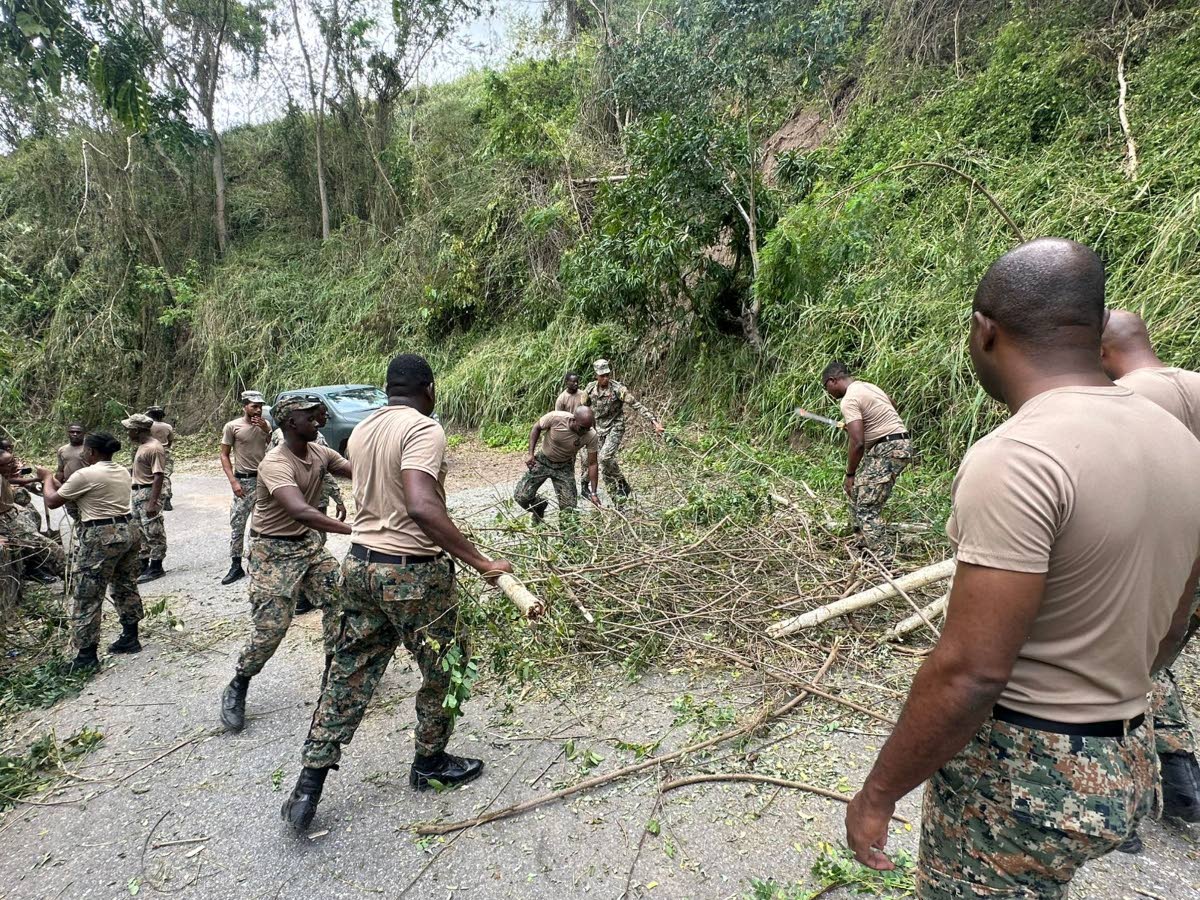 Jamaica Defence Force soldiers clear a section of roadway in hurricane-battered St Elizabeth.