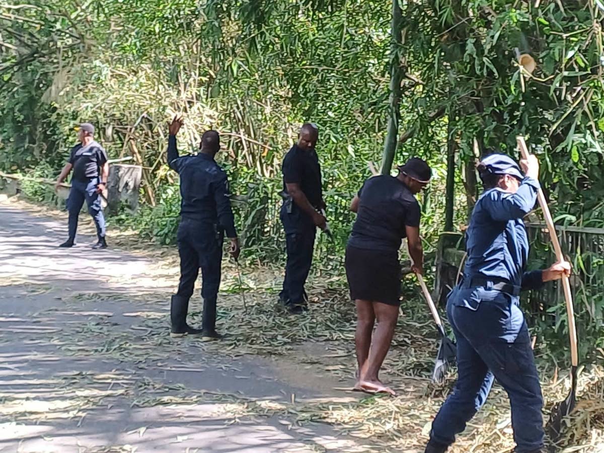 Police personnel and a community member clear debris caused by Hurricane Melissa, in the Guanaboa Vale community in St Catherine.