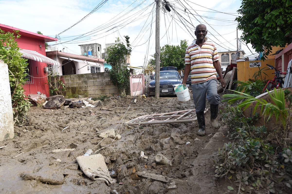 Retired firefighter John Lee tries to avoid walking in mud as he made his way along Rose Path in Westgreen in Montego Bay, St James, last week.