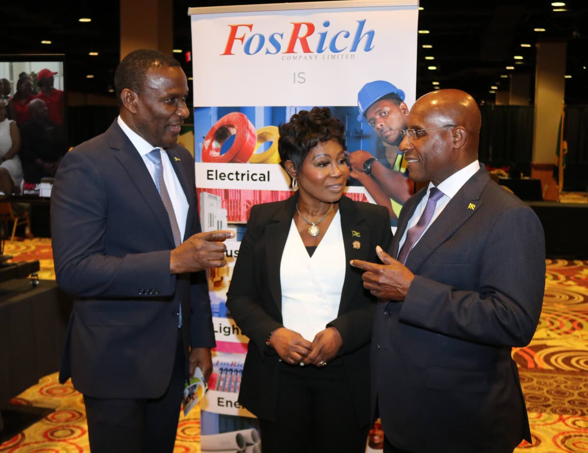 Minister of Industry Investment and Commerce Senator Aubyn Hill (right) engages FosRich Group CEO Cecil Foster during a Jamaica Investment and Housing forum at the Resort World hotel in Queens, New York, while Jamaica’s Consul General to New York Alsion 