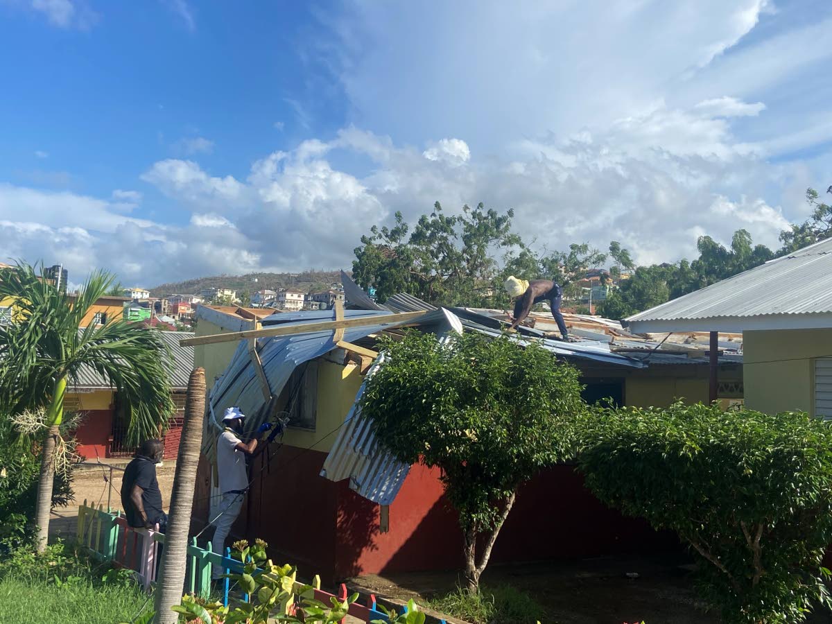 Volunteers fix a classroom roof damaged by Hurricane Melissa.