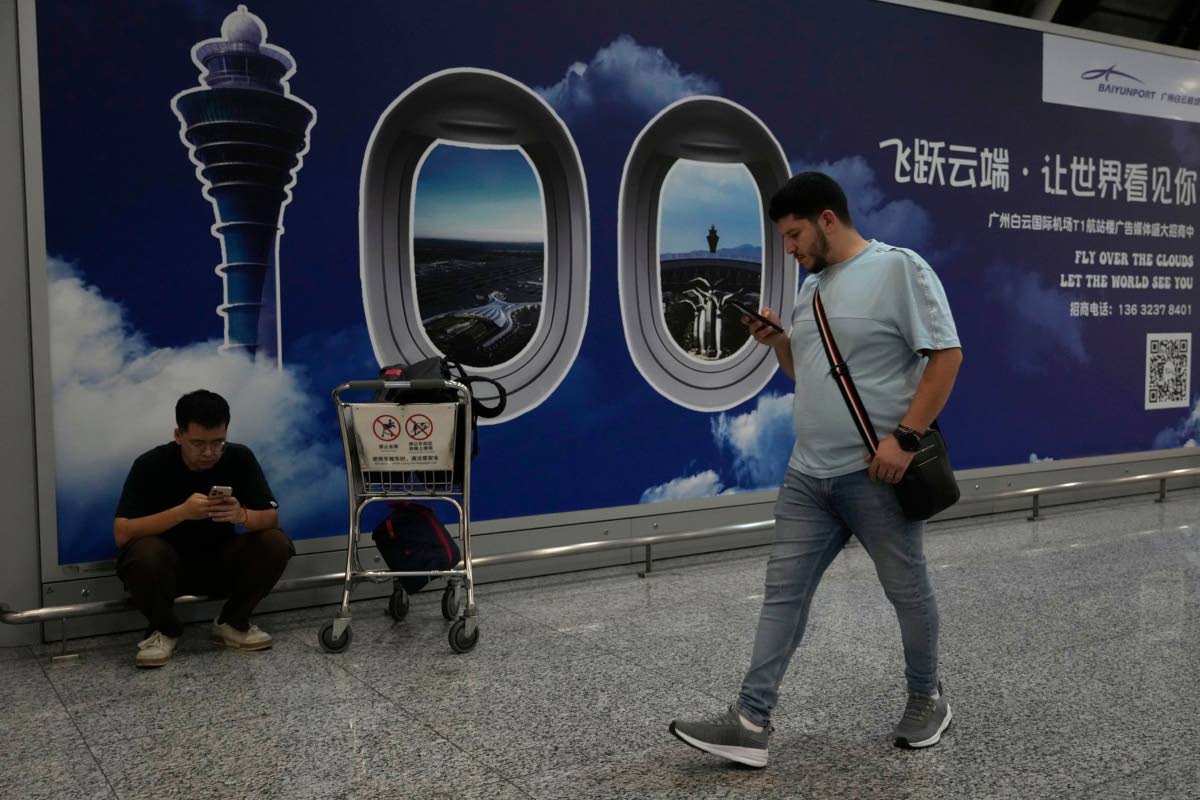 A foreigner walks past a sign board for the Baiyun airport in Guangzhou, southern China’s Guangdong province, on November 6, 2025.