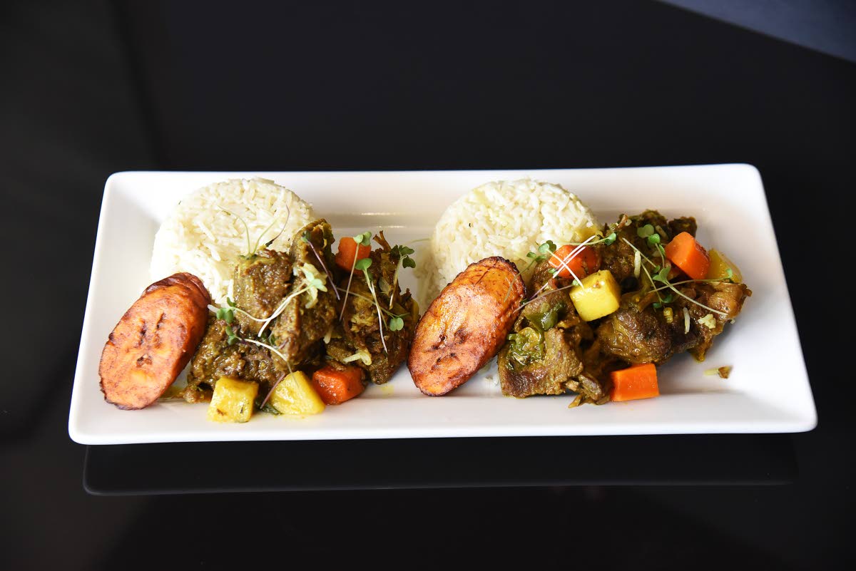 Local favourite, island curry, is paired with coconut-infused white rice and a side of fried plantains. 