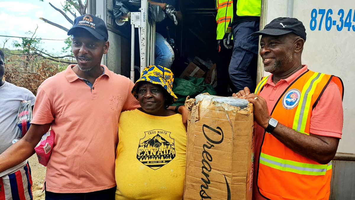 Dwayne Vaz (left), member of parliament for Central Westmoreland, and Mayor Leon Thomas (right) stand with Daphine Green (centre) after presenting her with a bed.
