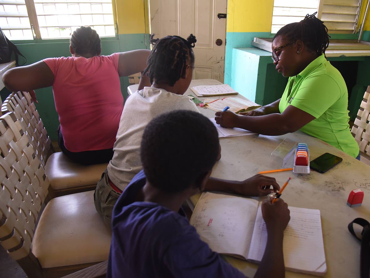 Allison Johnson (right), a teacher at Godfrey Stewart High, going through a lesson with primary school children at the shelter last week.