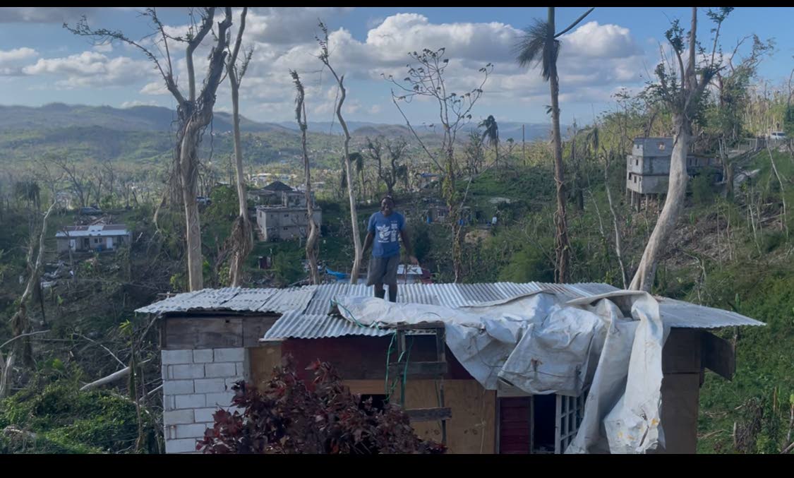 Donald Beckford putting on the roof to his small house that he rebuilt over the previous two weeks.