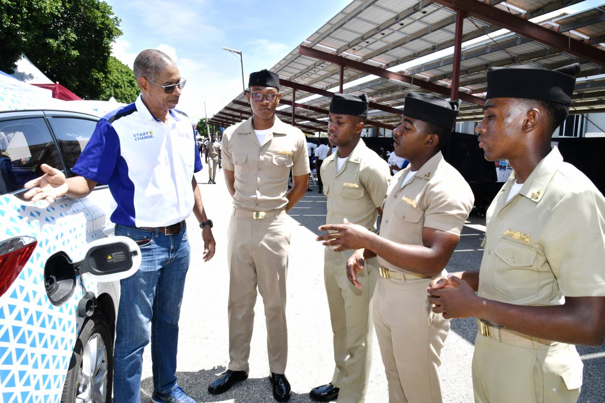 Richard Gordon (left), manager of business development at JPS, engages Caribbean Maritime University students on the Charge ‘n Go network and the advantages of electric mobility.