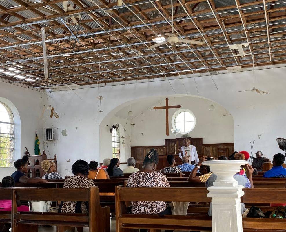Amid exposed beams and storm damage, Archdeacon Hollis Peter Lynch conducts a Eucharist at Christ Church Marley Anglican Church in Adelphi, St James, on November 23, as residents gather in faith and resilience after Hurricane Melissa.