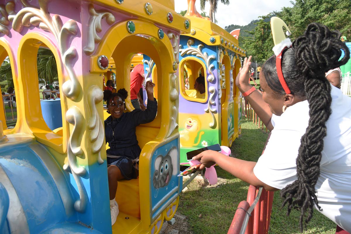 Keisha Sutherland (right), waves to her daughter Shakeira Morris (left) as she rides on the train at the Funland at Hope Gardens in St Andrew during the Digicel Foundation Christmas Treat for special needs children yesterday.  