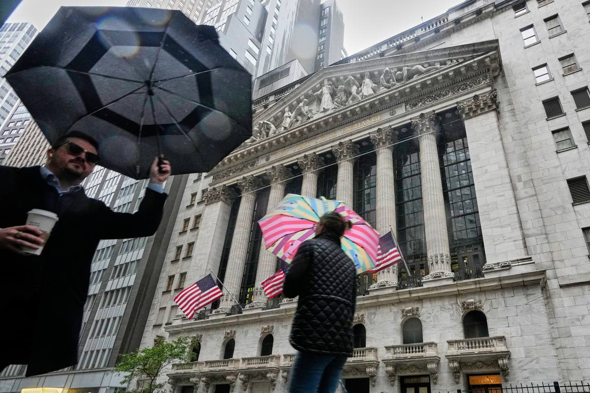 
People with umbrellas pass the New York Stock Exchange on Monday, October 13, 2025.