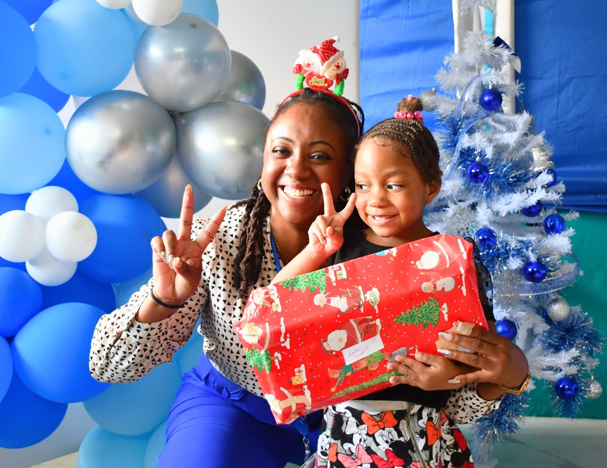 Akeela Marin, senior manager for business development, marketing and member relations at the Shipping Association of Jamaica (SAJ), presents a Christmas gift to Aazia Simmonds of the Marcus Garvey Basic School.