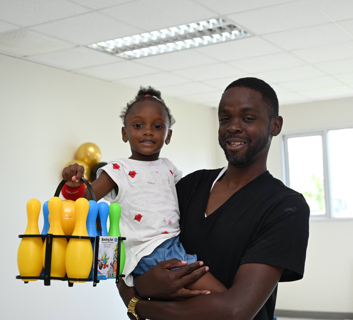 Little Khaylya Harvey, after receiving her bowling set, poses with her father, Dane Harvey, during the Montego Bay Free Zone and Global Services Association Jamaica post-Hurricane Melissa Christmas treat for Catherine Hall and Westgreen residents in St Jam