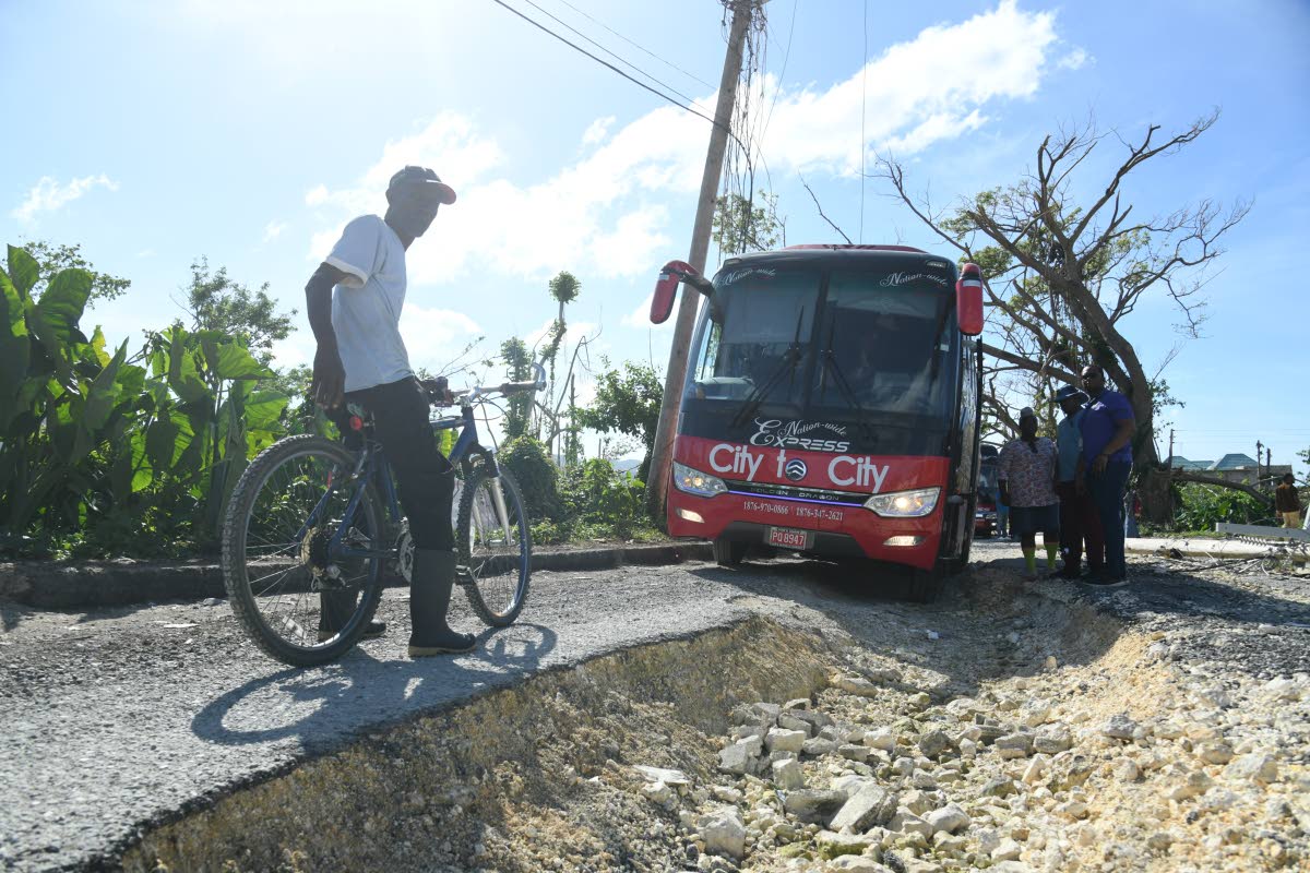 Napolean Turner, resident of Rolling River, stops near volunteers of the Faith Chapel of Faith Apostolic Ministries as they disembark the bus they were travelling on when it got stuck in a pothole along the Rolling River main road in Shrewsbury Westmorelan