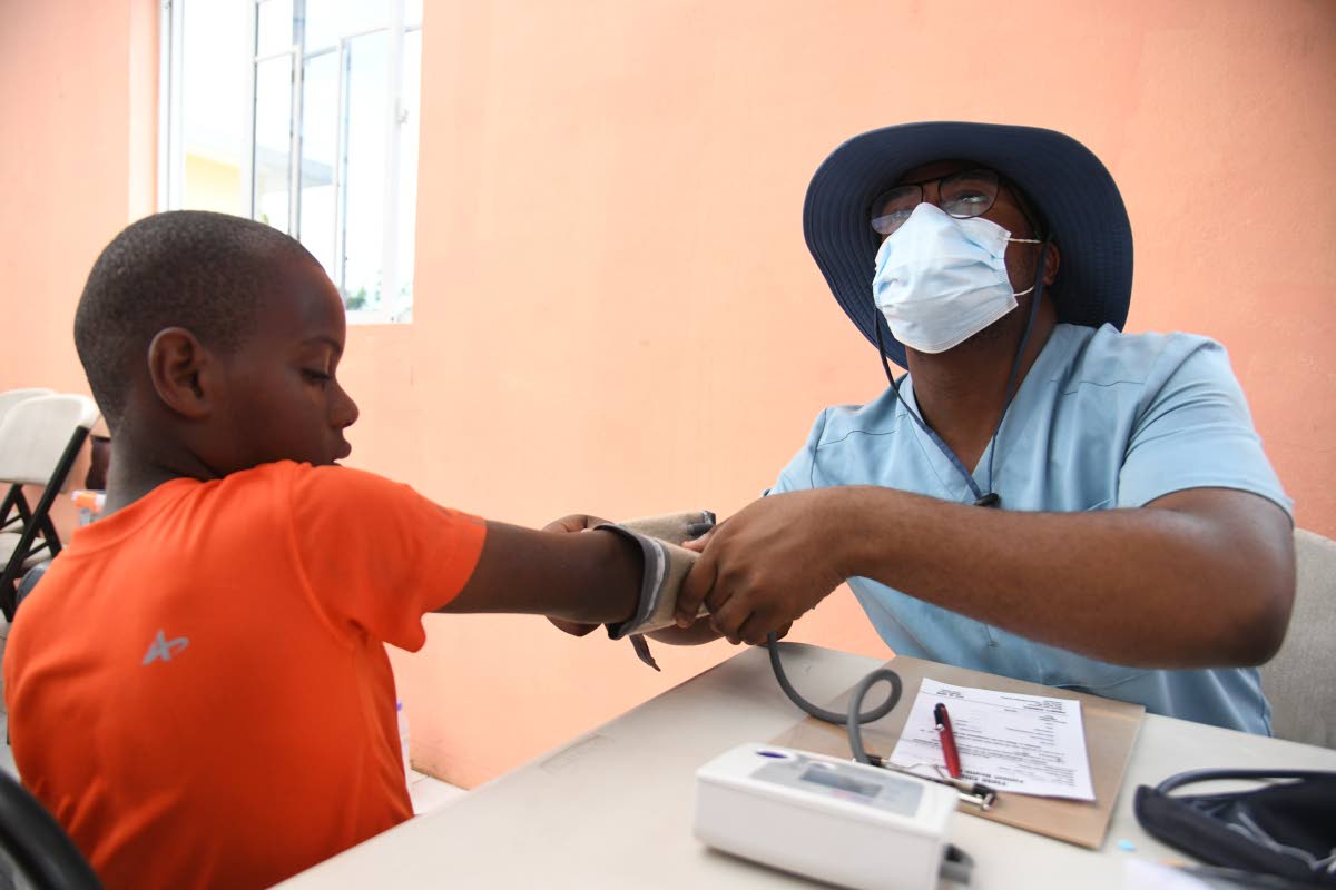 Alex Johnson, head of the Faith Chapel of Faith Apostolic Ministries Health and Welness Department, attends to a patient on December 13 at the Mother Lewis AME Church in Shrewsbury, Westmoreland. 