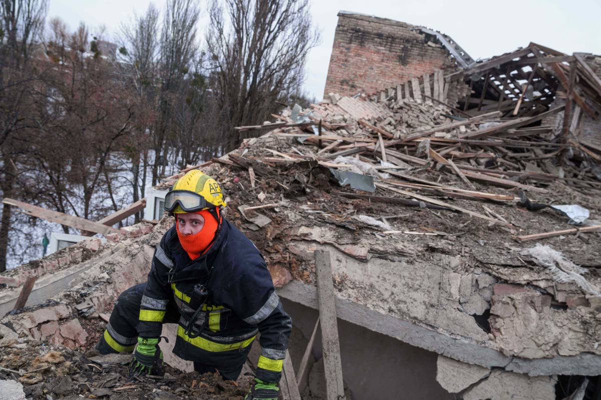 A rescue worker climbs onto the roof of an apartment building damaged after a Russian strike on Kyiv, Ukraine.