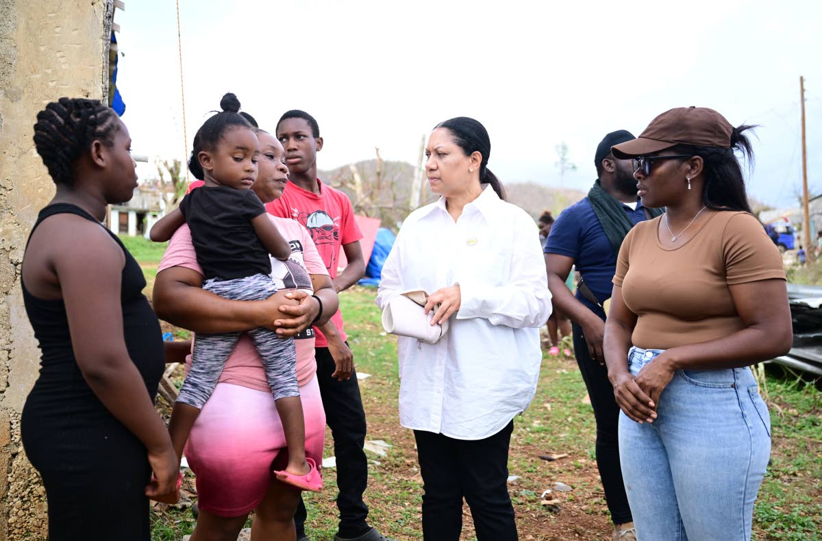 Custos of Clarendon Edith Chin (second right) speaks with Ashella Baker (second left) from Middle Quarters in St Elizabeth, while in the community recently to hand over a container house to the mother of six. Sharing in the discussion is representative of 