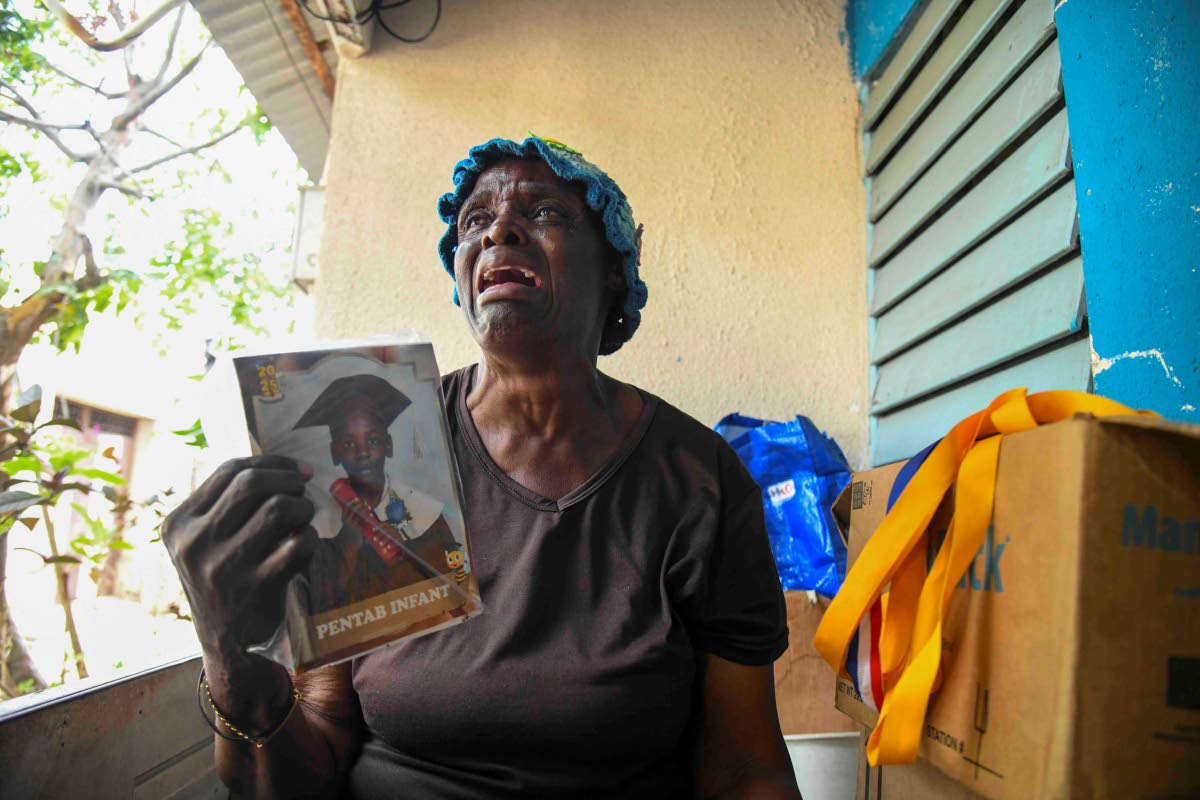 Fifty-nine-year-old Charmaine Faulkner, grandmother of six-year-old Josiah Lewis, who drowned on Tuesday, shows a photograph of him while speaking with The Gleaner at her home in Kingston yesterday.