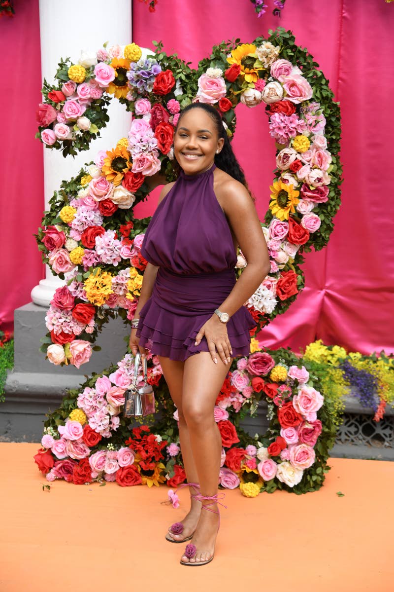 Destination marketing officer Sadé Johnson smiles for the camera in a purple chiffon high-neck playsuit dress paired with Bridget Rose sandals.