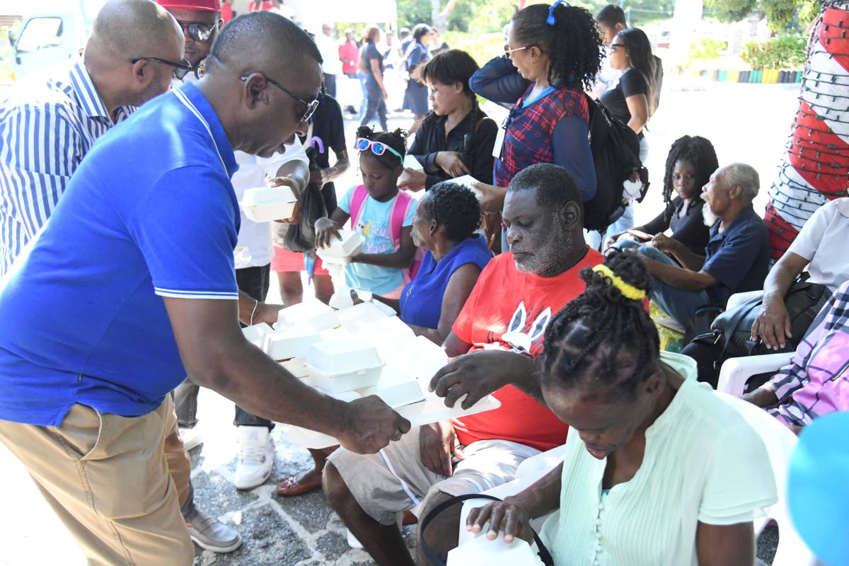 Mayor Andrew Swaby gives Delroy Hall a box of burger at the St. William Grant Park in Kingston on January 1, 2025.