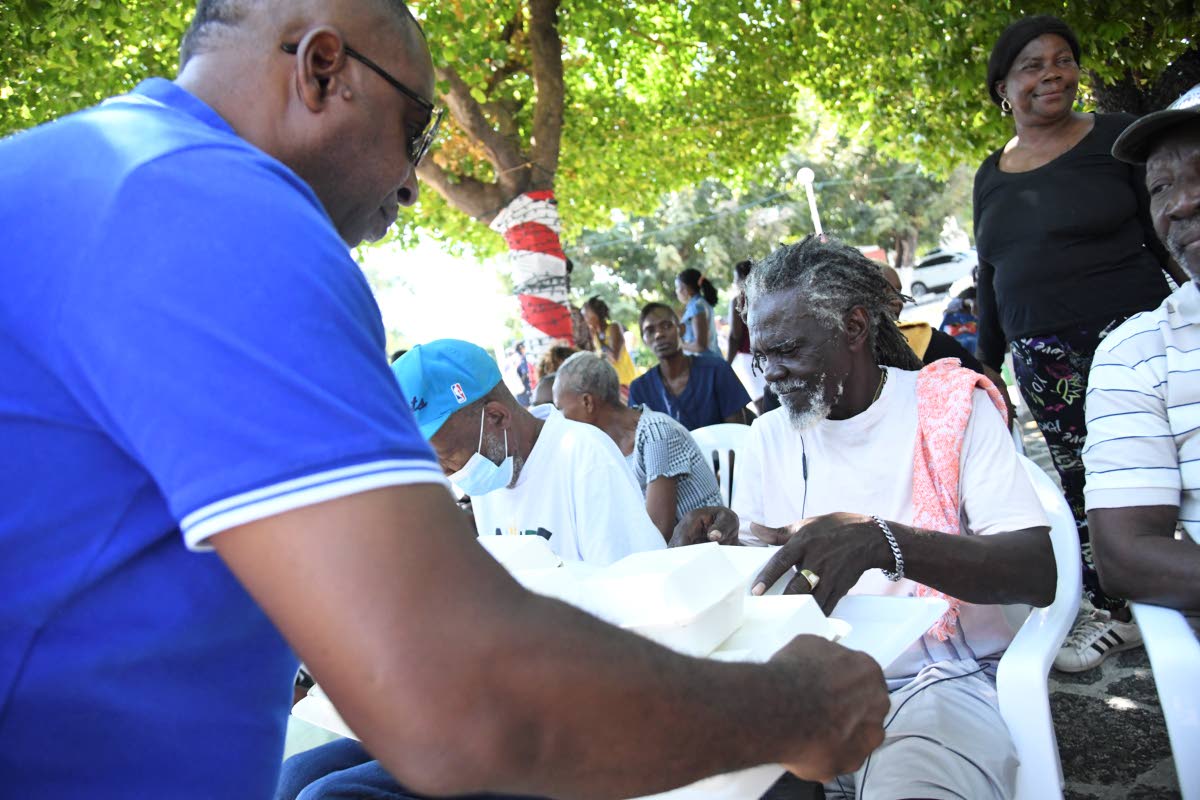 Mayor Andrew Swaby gives Abraham Grant a box of burger at the St. William Grant Park in Kingston on January 1, 2025.