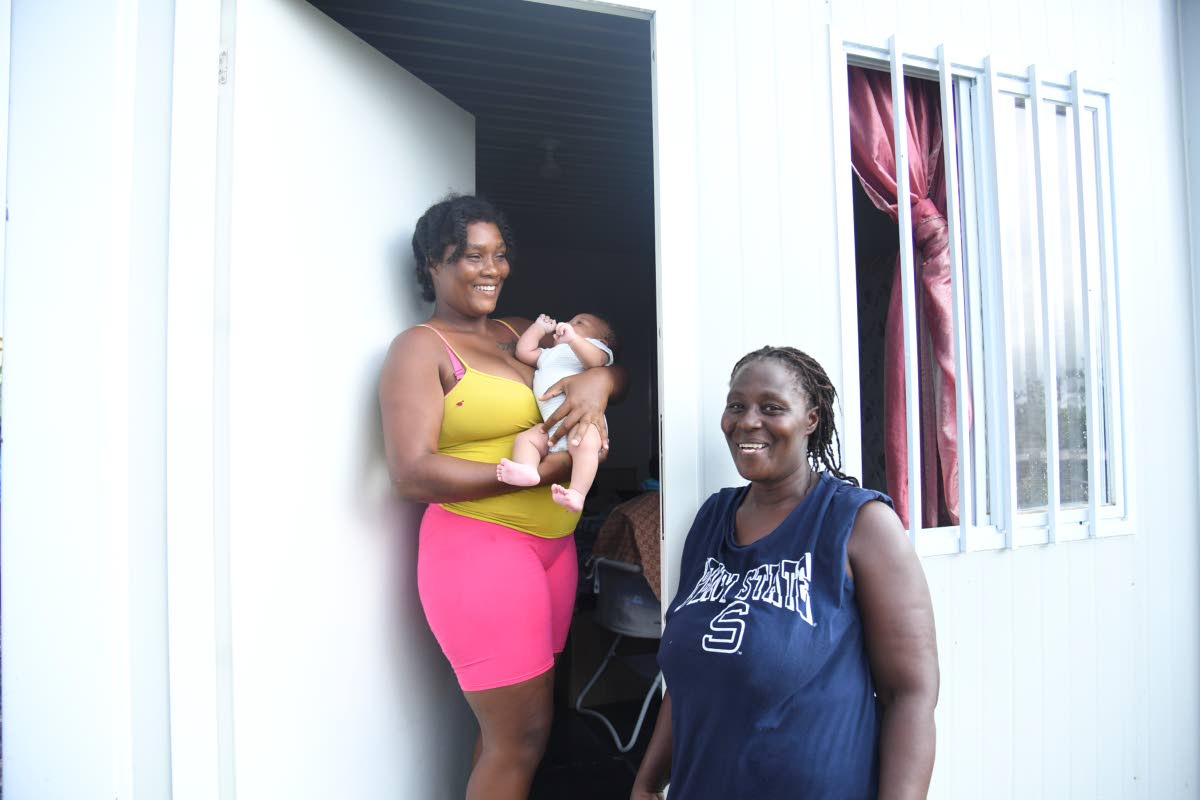 Crystal Morris (left), who spent days inside a van with several relatives during the latter part of her pregnancy, holds her son Dejaun Josephs last week while her mom Marcia Robinson looks on in front of their new container home in New Works, Westmoreland