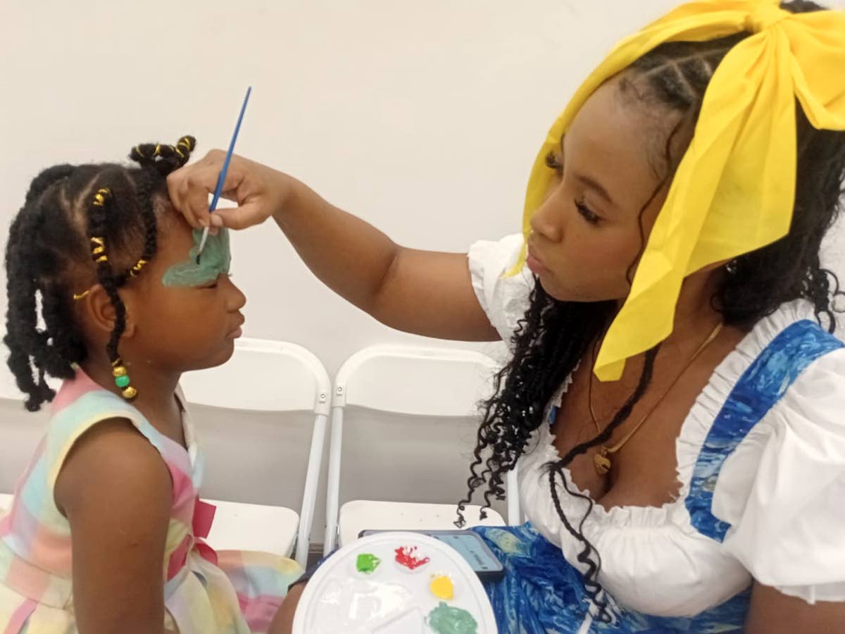 Visual artist and face painter Empress9ra delights children by painting a little girl’s face during TruFun Play’s grand opening on Saturday.