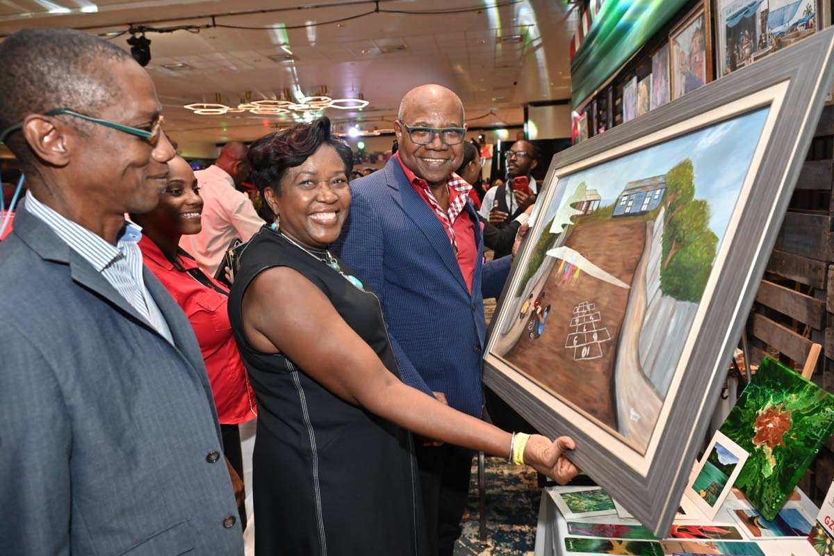 Artist Winsome Gibbs, CEO of Gzome Artistry, shows her painting to Edmund Bartlett (right), minister of tourism; and Christopher Jarrett (left), president of the Jamaica Hotel and Tourist Association, during a tour of Christmas in July at The Jamaica Pegas