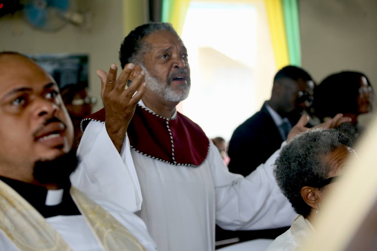 Captain Christopher Givans, associate evangelist, raises his hands in praise during the funeral service of Alvarene Roberts yesterday.