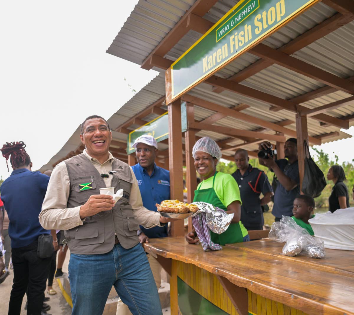 Prime Minister Dr Andrew Holness (left), laughs as he is presented with a large container of fried fish by a vendor at the reopening of shops in Border, St Elizabeth on January 16. 
