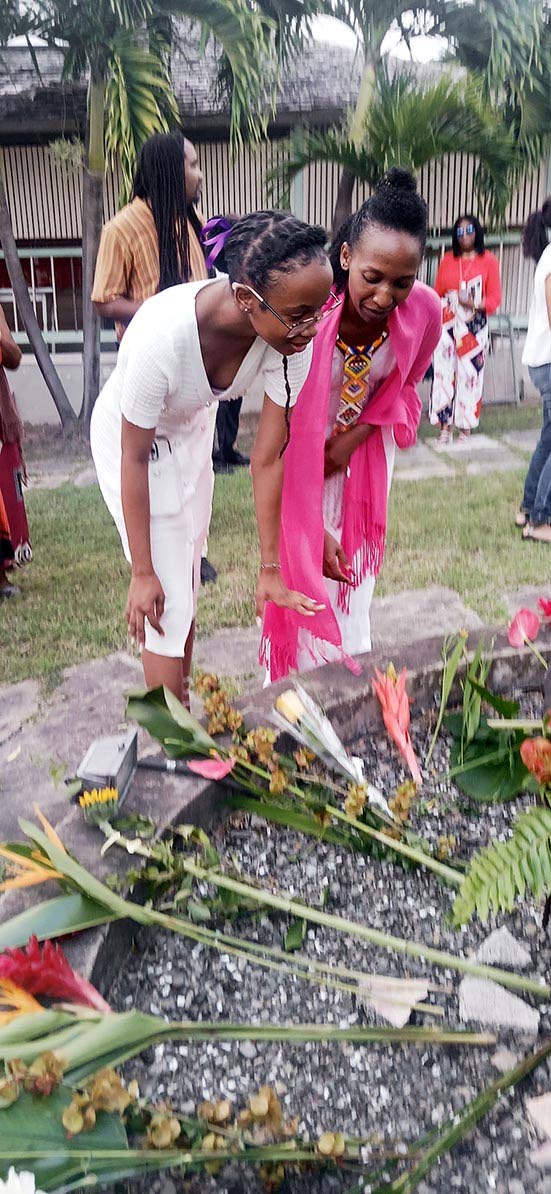 Left: Maguwa Wamazola and Meloddi Mazola laying flowers at the base of a Mazola sculpture.