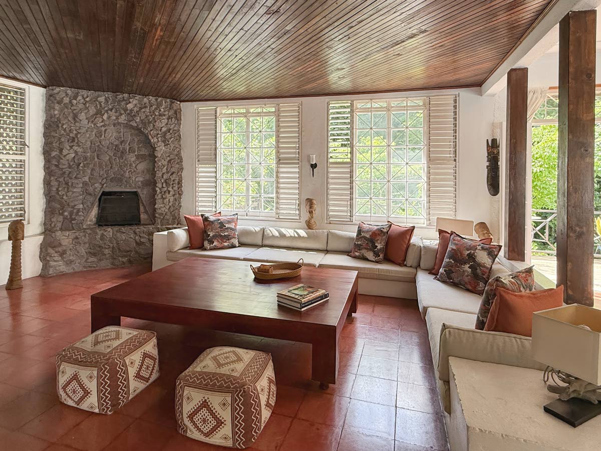 A sitting room with its stone fireplace, faces the river jungle and Koi fish pond below.