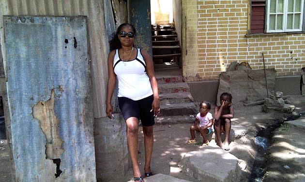 Evelyn Carridice, the sister of the late Bunny Wailer, standa in front of the stairs leading up to the house where she, Jah B, their parents and siblings lived.
