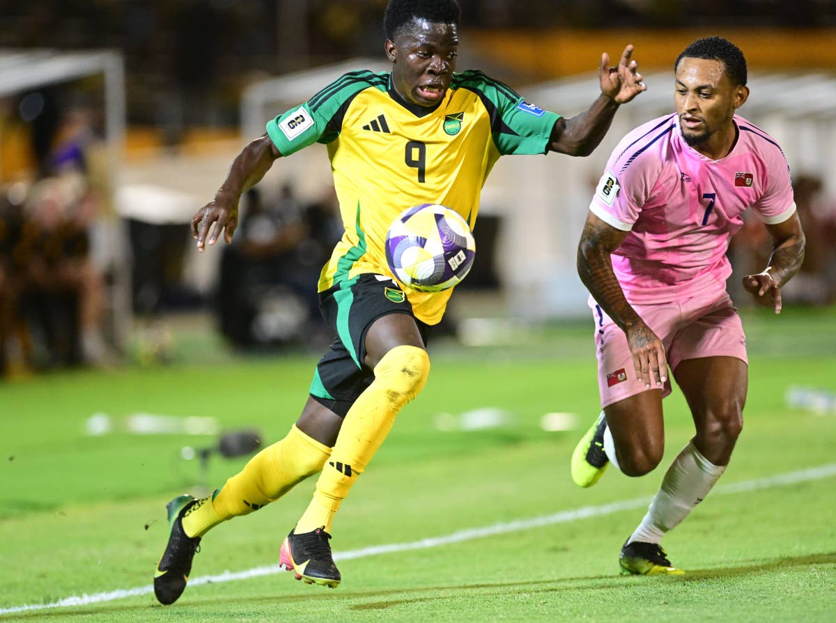 Jamaica's Kaheim Dixon (left) powers past LeJuan Simmons of Bermuda during a Concacaf Group B World Cup Qualifying match at the National Stadium. 