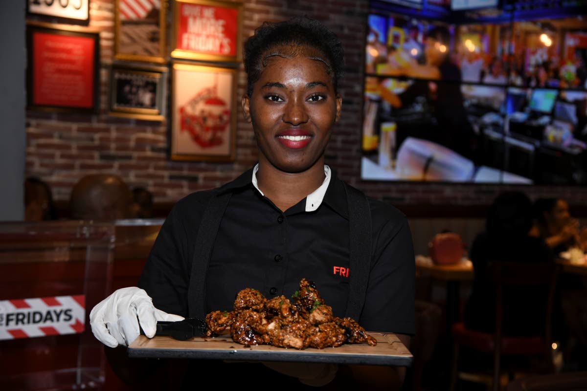 A waiter or waitress is always ready to serve the restaurant’s signature dishes with a smile. Here, Brittanica Taylor shows us the whiskey glazed boneless bites.