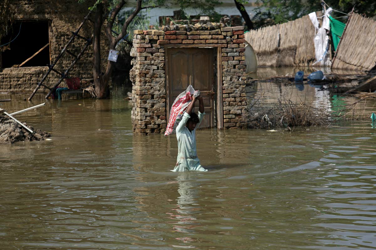 
A man carries usable belongings salvaged from his flood-hit home across a flooded area in Shikarpur district of Sindh province of Pakistan on August 31, 2022.