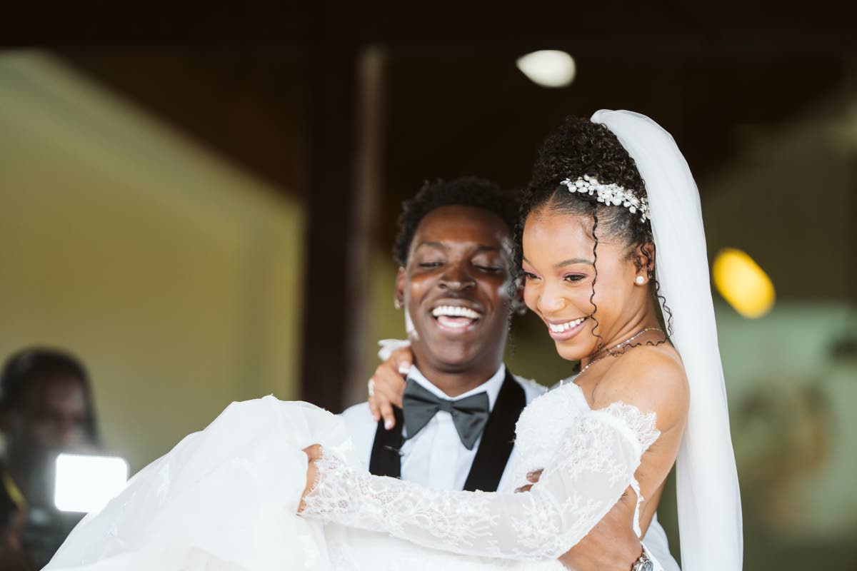 Beaming with joy, Dalkeith lifts his bride, Rohanna, as they exit the Constant Spring Church of Christ in St Andrew.