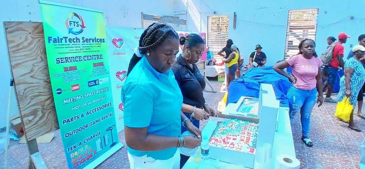 Janet Richards (left), founder of the Janet Richards Foundation, and Nathalie Fairweather, manager of Fairtech Services Limited in Montego Bay, St James, prepare to serve refreshments to residents of Chatham, St James.