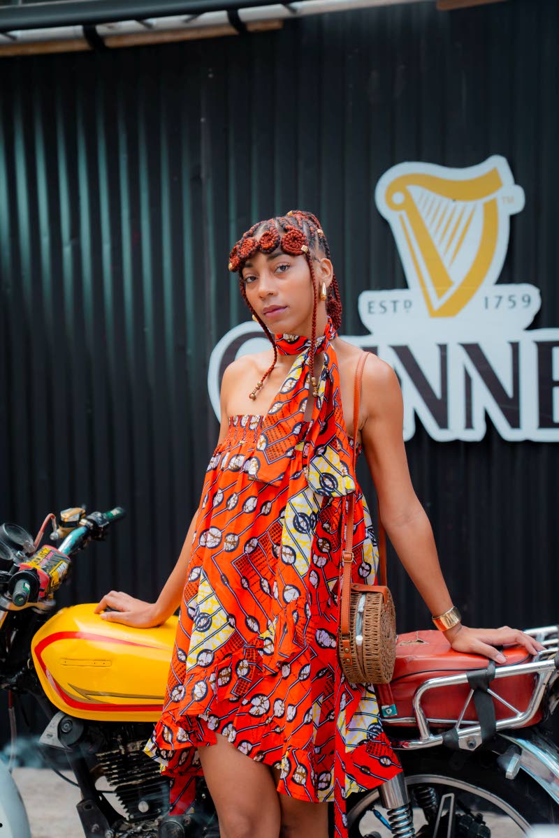 Dominique Richards showcases her assured sense of style in a flared mini cut from vibrant wax print, finished with a coordinating scarf and rattan crossbody bag. 
