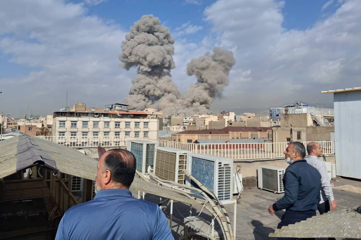 People watch as smoke rises on the skyline after an explosion in Tehran, Iran on February 28, 2026.