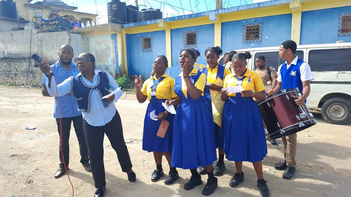 Students of Maud McLeod High School perform a Peace Day item at the Darliston bus park, accompanied by Principal Beverley Feare (second left) and guidance counsellor Laten Williams (left).