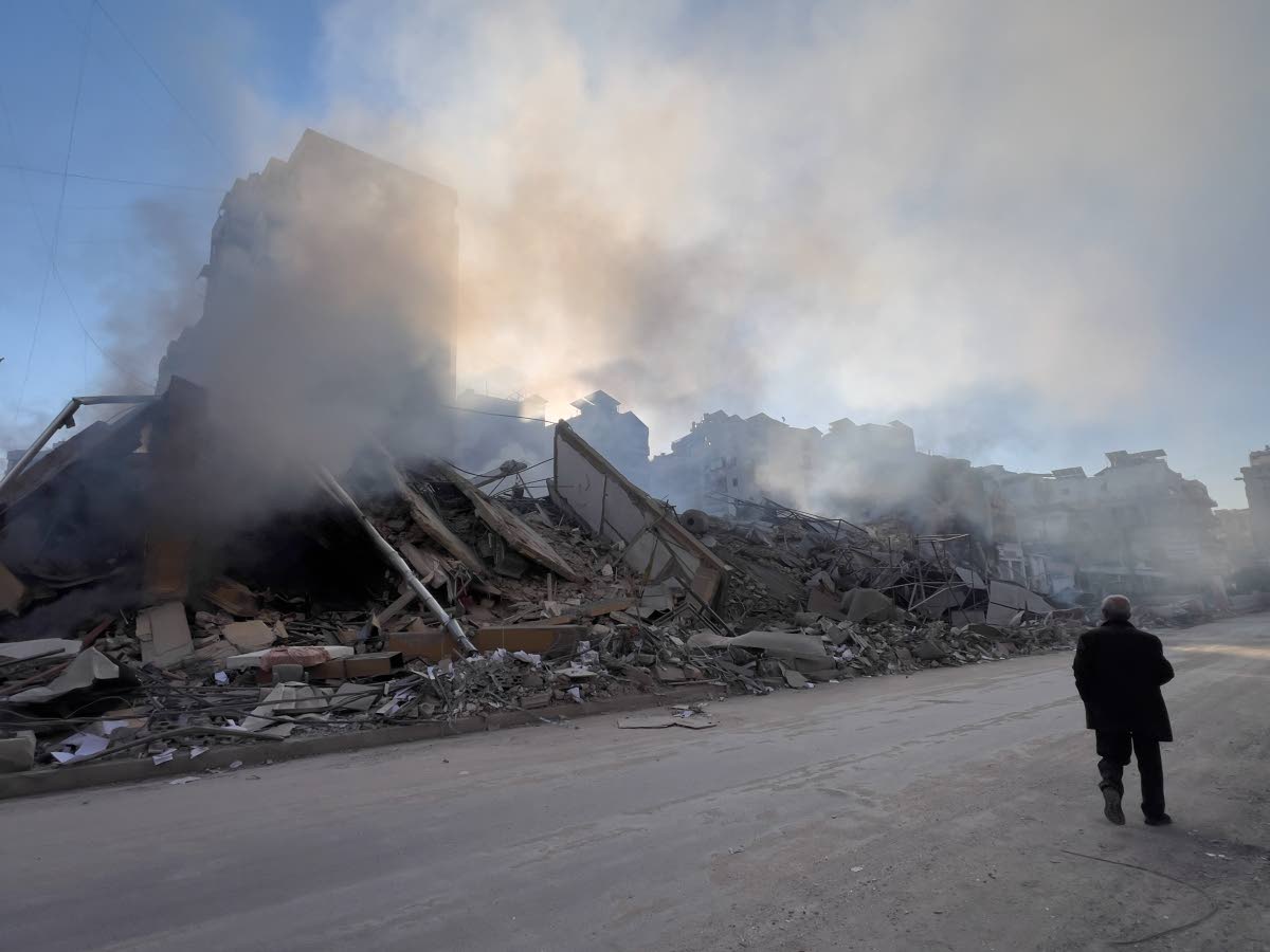 A man passes in front of a destroyed building that housed a branch of Al-Qard Al-Hassan, a non-bank financial institution run by Hezbollah, which was hit by an Israeli airstrike in Dahiyeh, Beirut's southern suburbs, Lebanon on March 10, 2026. (AP Photo/Hu